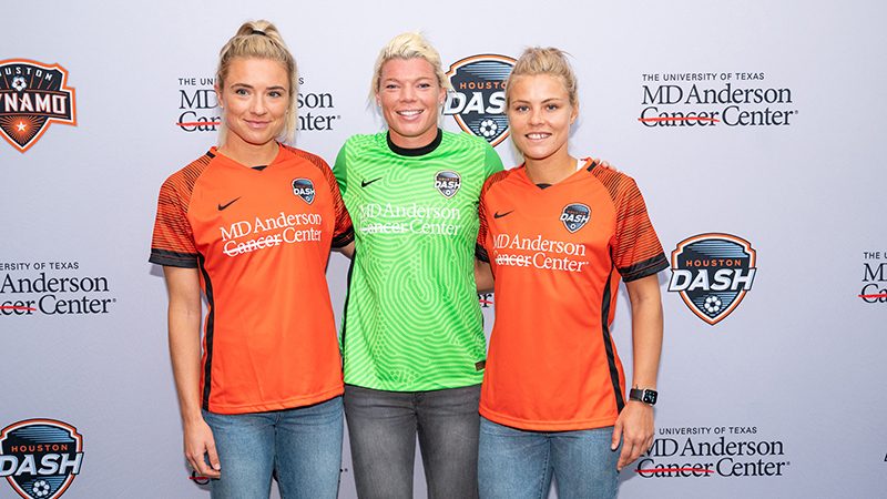 Kristie Mewis，Jane Campbell和Rachel Daly穿着橙色和绿色MD Anderson-Branded Houston Dash Jerseys